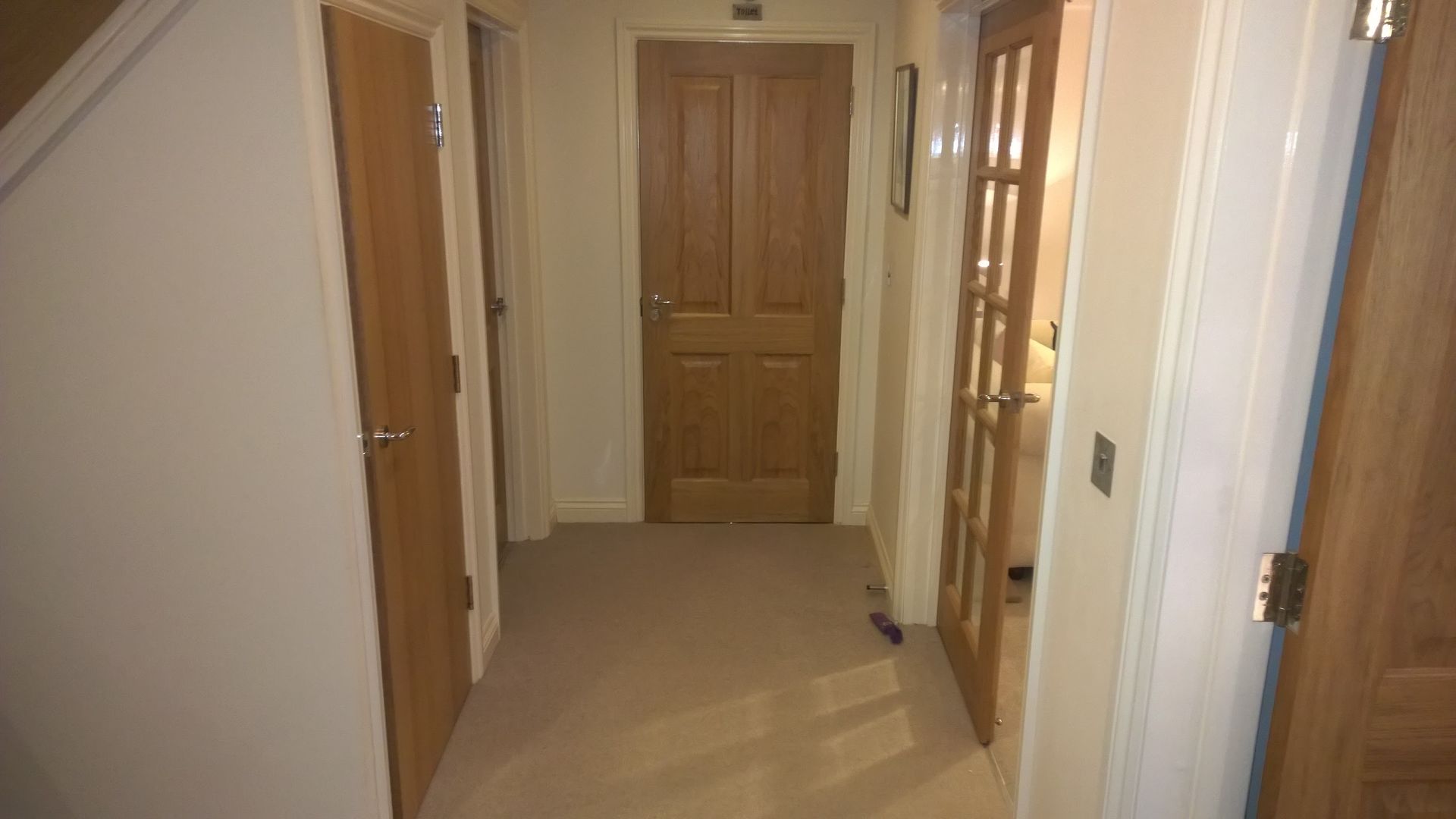 A hallway with wooden doors and stairs in a house.