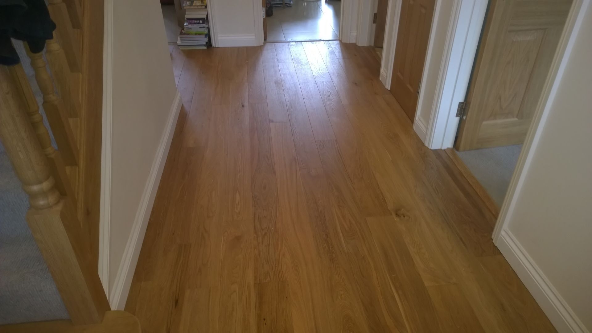 A hallway with a wooden floor and stairs in a house.