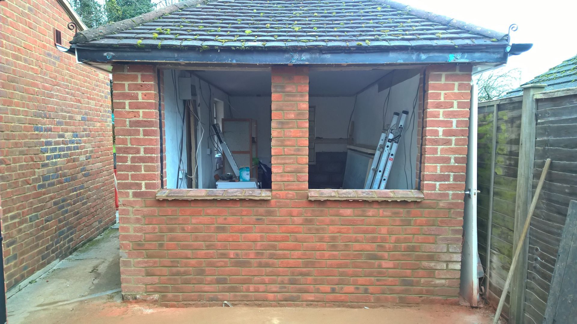 A brick building with a window and a ladder in the backyard.