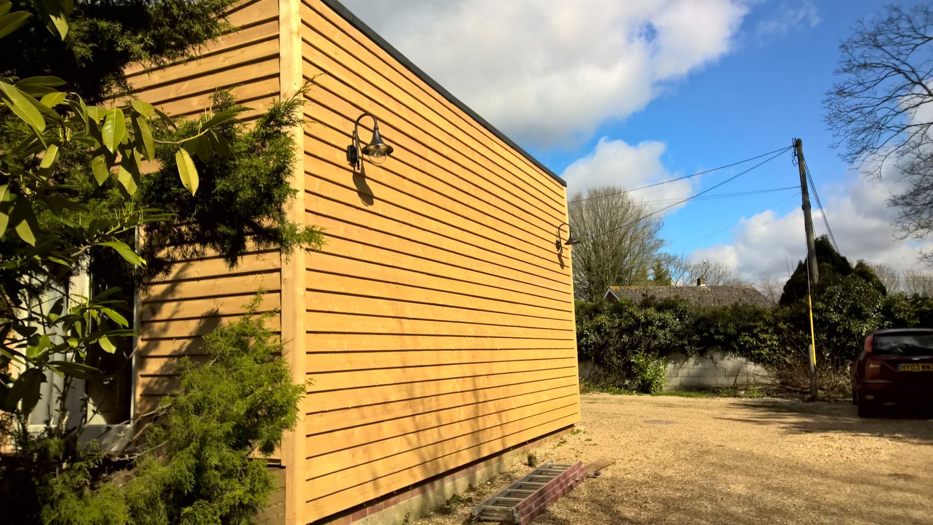 A car is parked in front of a wooden building.
