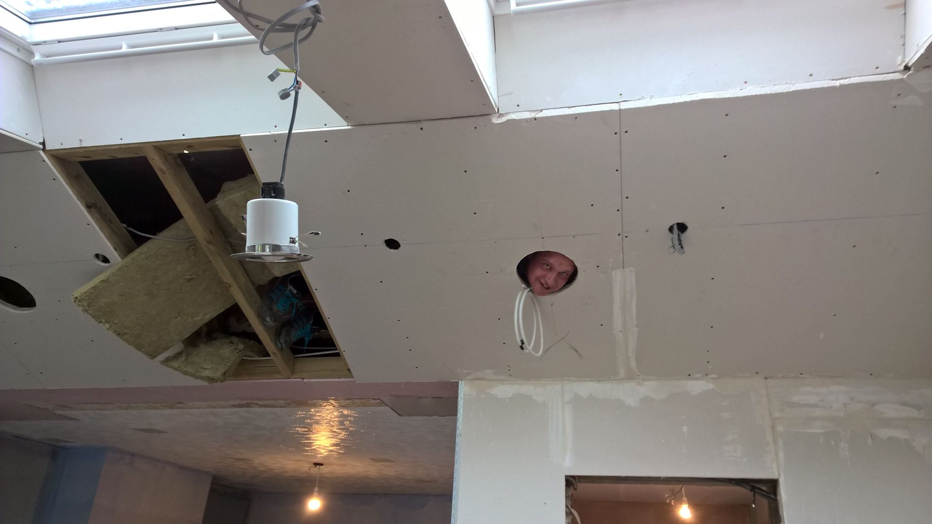 A ceiling with a hole in it and a light hanging from it.
