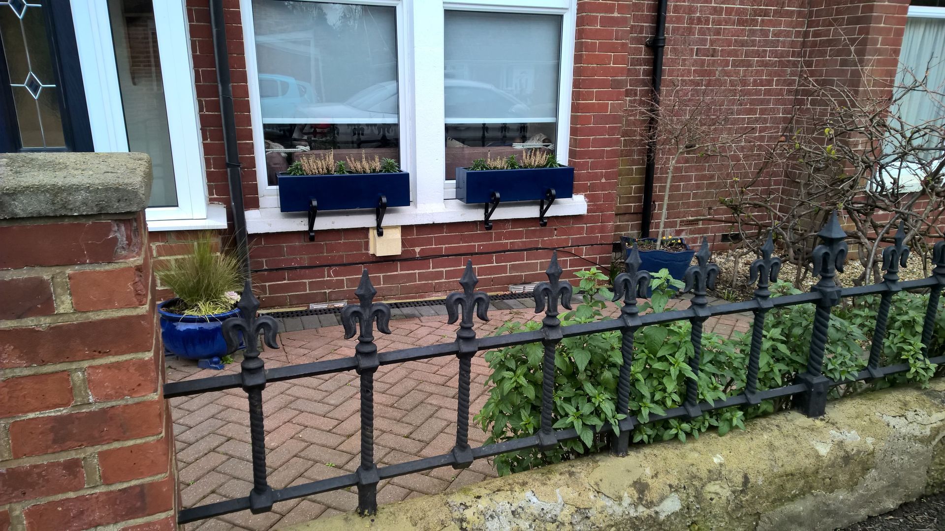 A black wrought iron fence is surrounding a brick house.