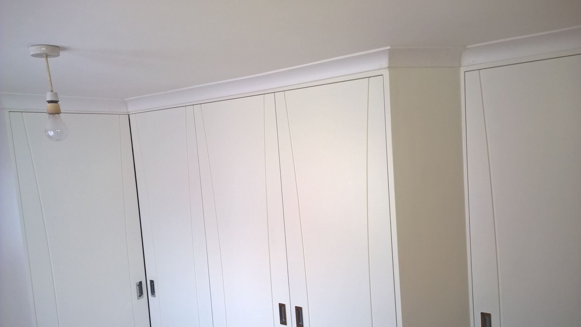 A room with white cabinets and a light bulb hanging from the ceiling.
