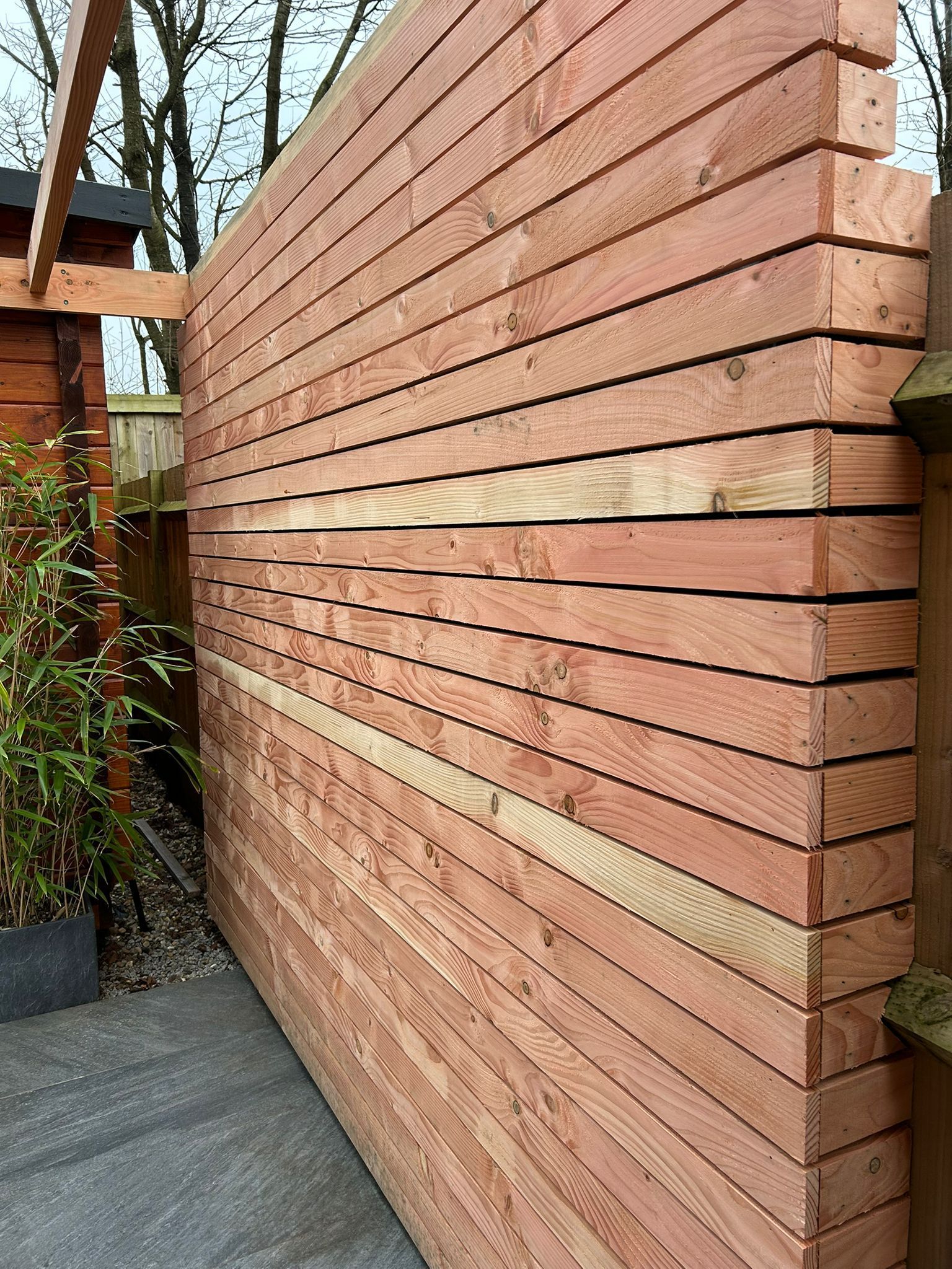 A large wooden wall with a fence in the background.