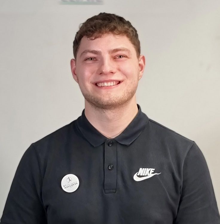 Daniel Daniel's portrait in in a blue shirt and grey west. He is sports therapist and is working for Total Massage Limited.