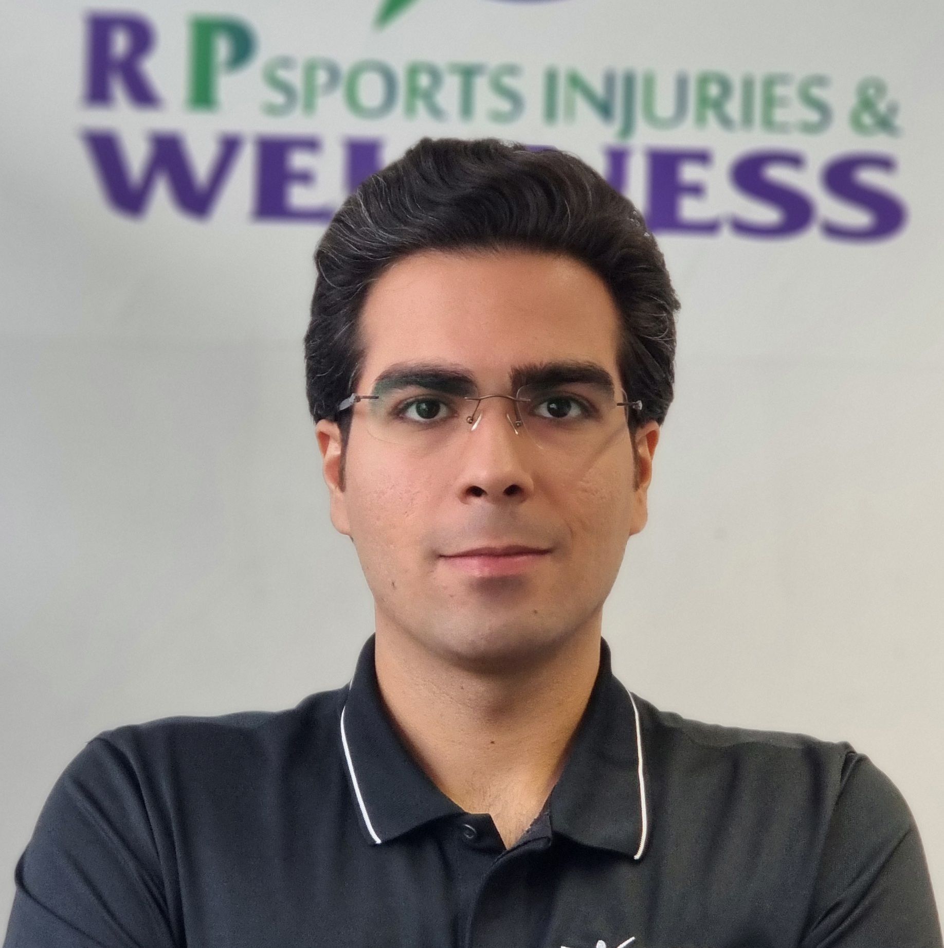 Mohammad Mark, a dedicated Sports Therapist wearing glasses and a black collared shirt with white trim