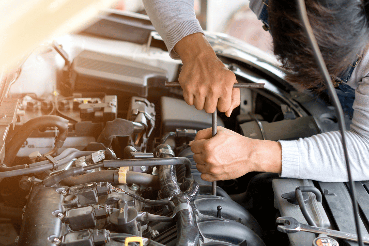 Mechanic using a wrench to repair a car engine under the hood