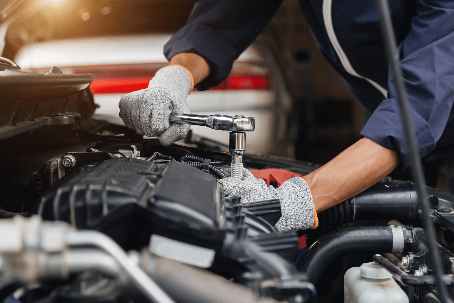 Mechanic using a ratchet wrench to repair a car engine in a garage