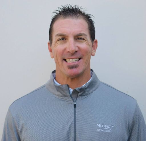 A man in a white shirt is smiling for the camera.