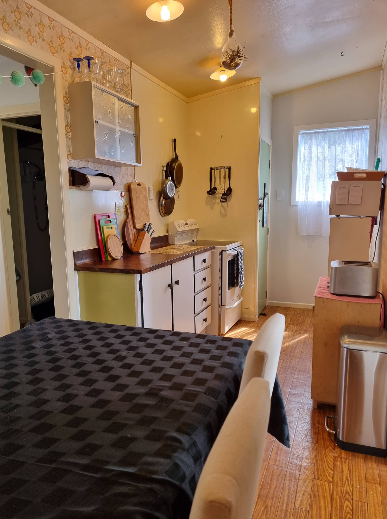 Small bach kitchen, white cabinets, and a doorway with light from a window.