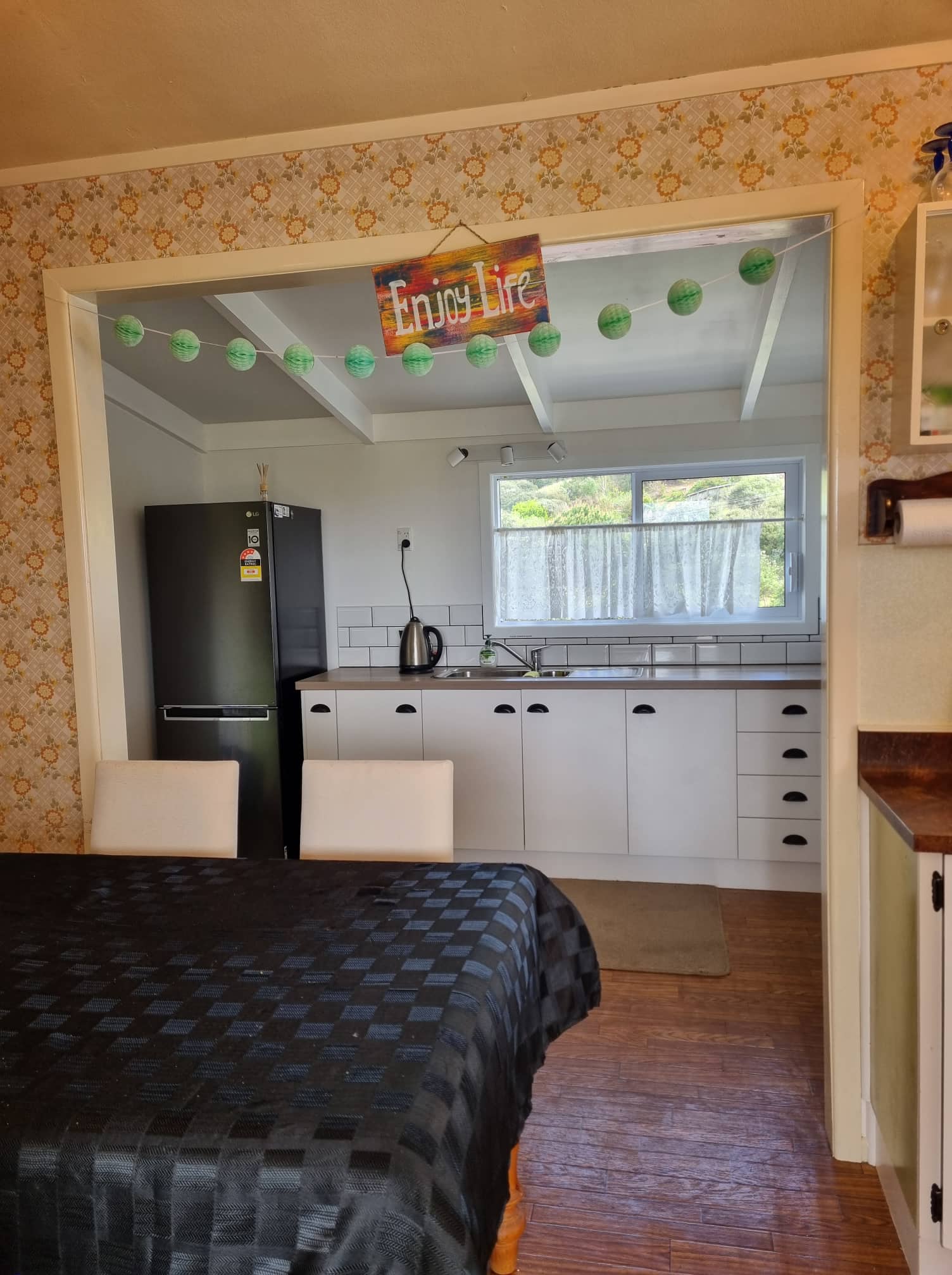 Dining table looking into a white kitchen