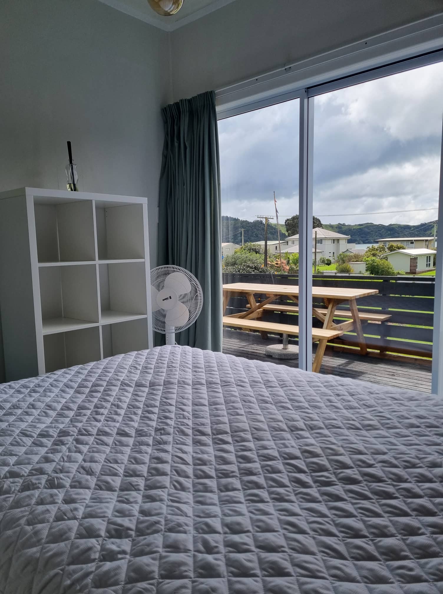 Bright bedroom with sliding door to a balcony with picnic table.