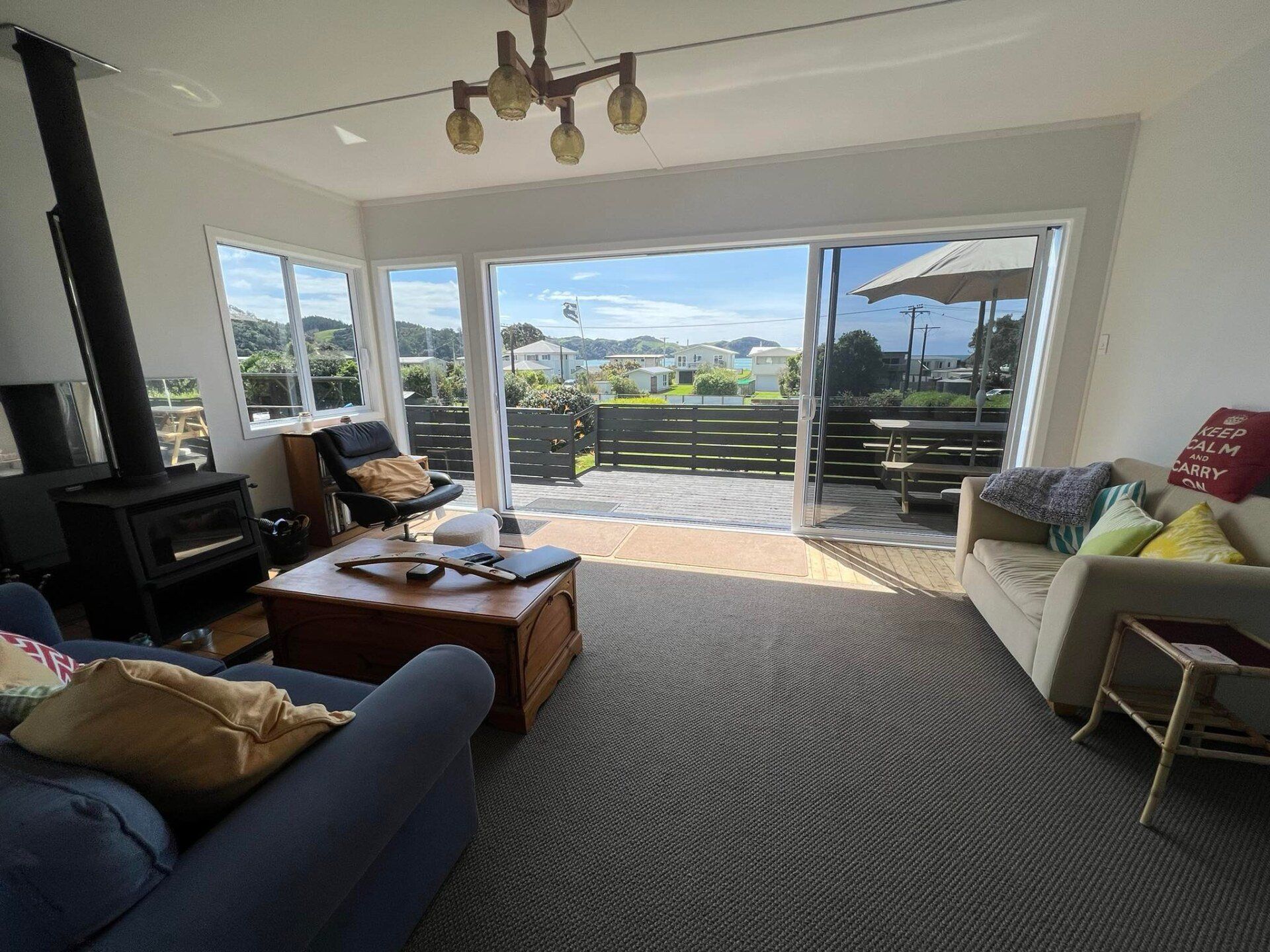 Living room with ocean view through wide sliding glass doors, blue sofa, coffee table, and patterned rug