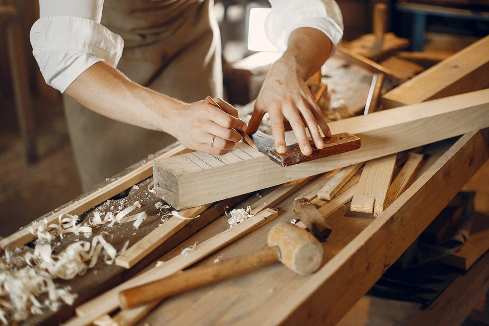 A man is using a drill to drill a hole in a piece of wood.