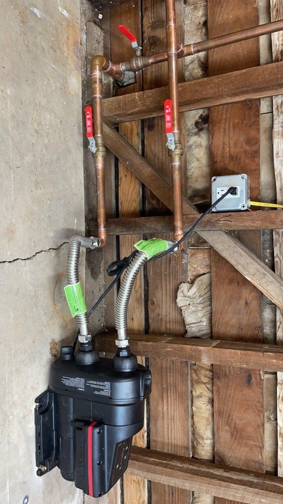 Black handheld device with cables and tubes mounted on a wooden wall in a workshop.