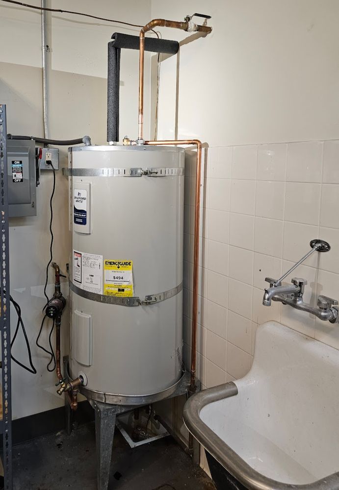 Water heater with copper pipes beside a utility sink in a bathroom or basement utility area
