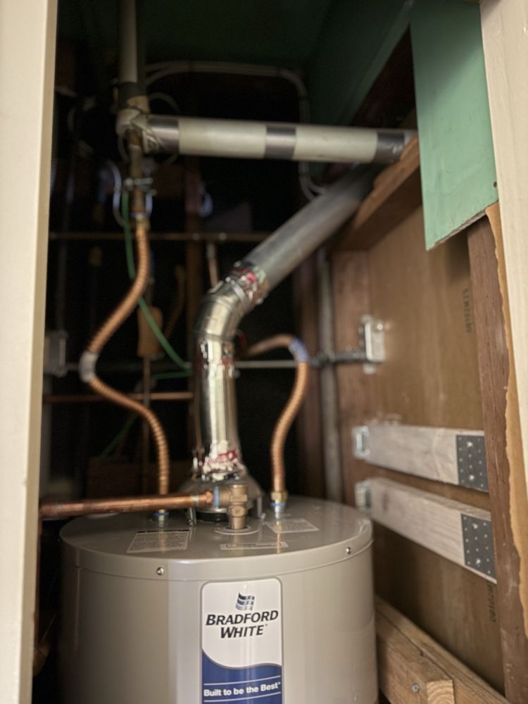Water heater in a utility closet with copper pipes and a vented exhaust pipe.