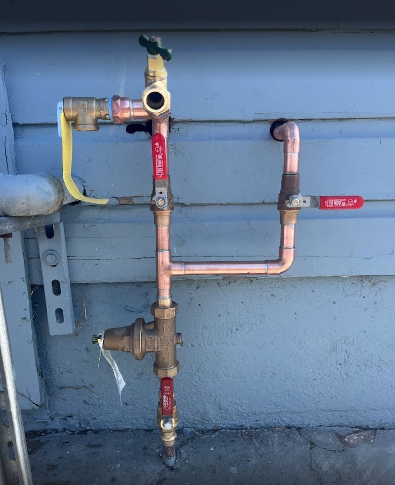 Outdoor gas pipe with red shutoff valves mounted on a house wall