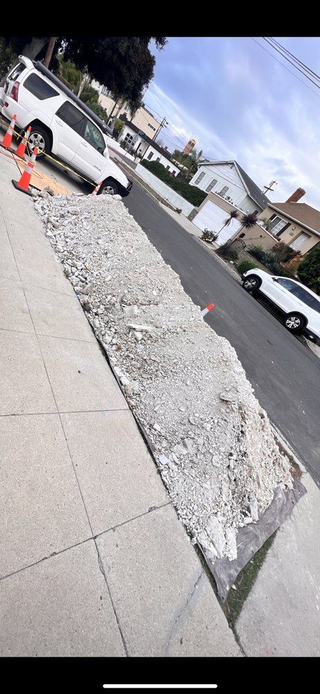 Tilted street view of a white pickup near a broken sidewalk and gravel strip in a residential neighborhood