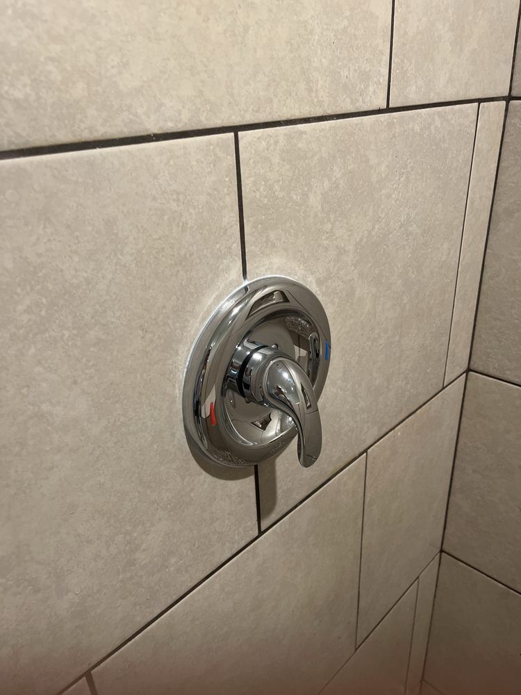 Chrome shower control lever on beige tiled bathroom wall