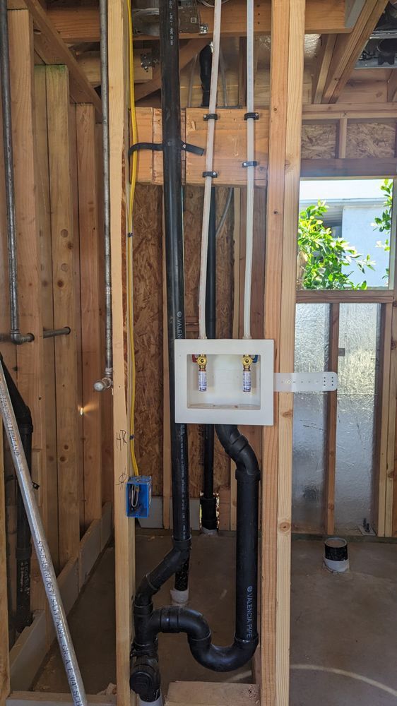 Framed wall with exposed pipes and electrical box during home construction.