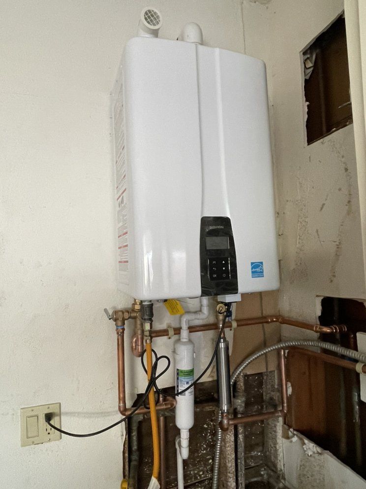White wall-mounted water heater with exposed pipes in a small utility room