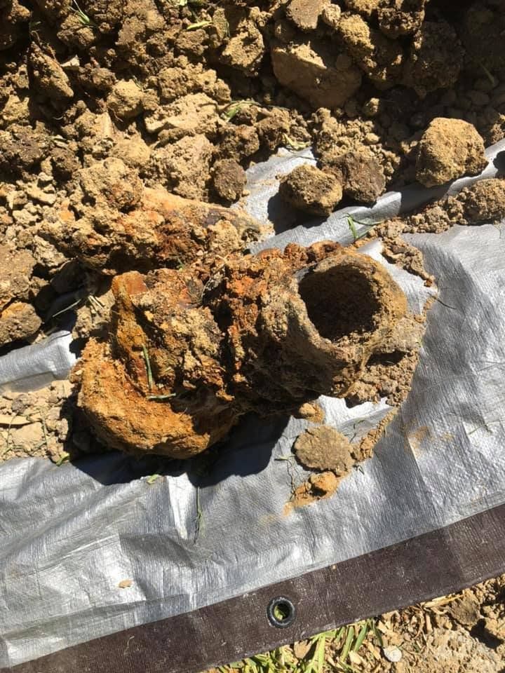 Rusty corroded metal object lying on dirt and a tarp at a construction site