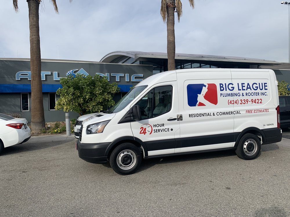 White Big League van parked outside an Atlantic building on a cloudy day.