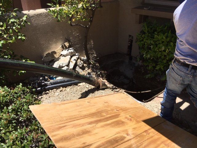 Wooden board at an outdoor construction site with a worker standing nearby and debris in the background