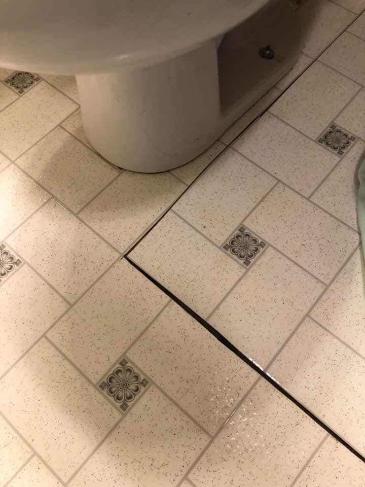 Bathroom floor with light tile and a toilet base