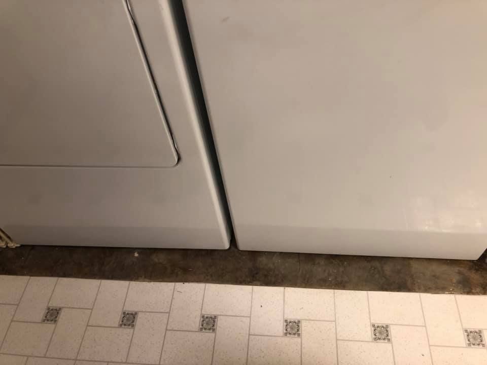 Close-up of white cabinet doors above a beige tiled floor with dark grout and a dark edge strip.