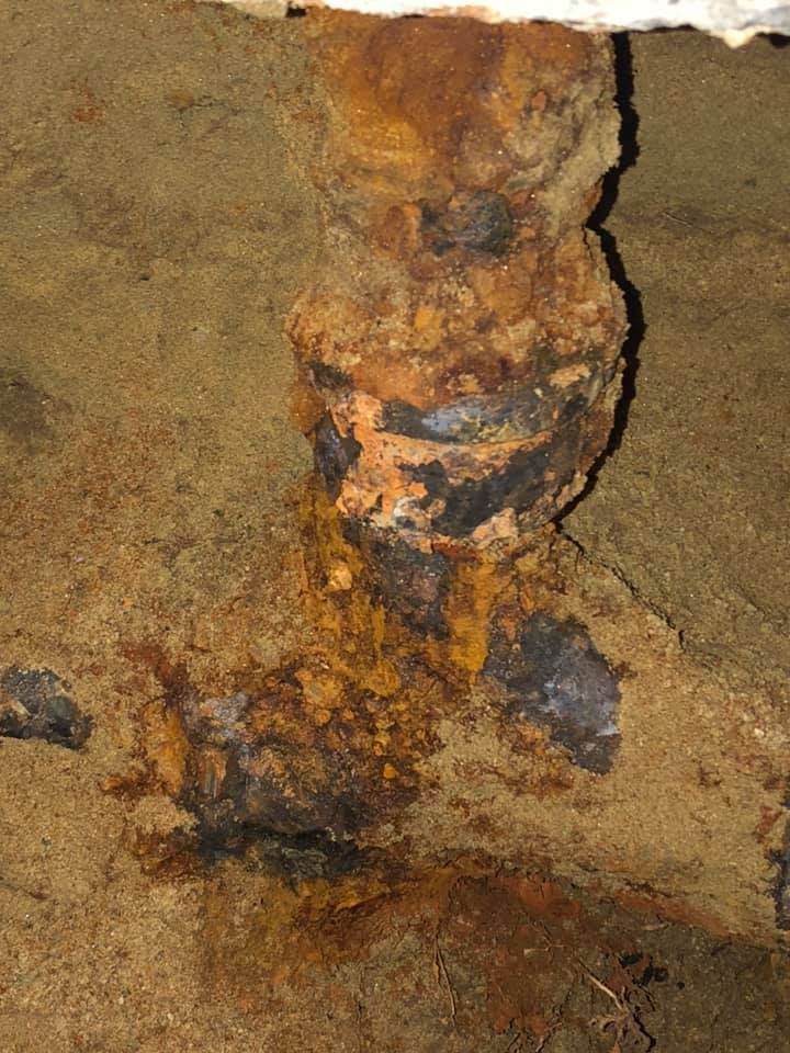 Close-up of a rusted, corroded metal surface with orange and brown stains on a rough background