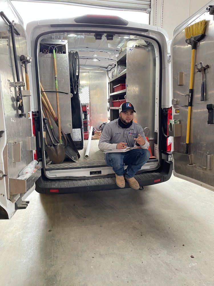 Person sitting in the back of a white utility van in a workshop garage