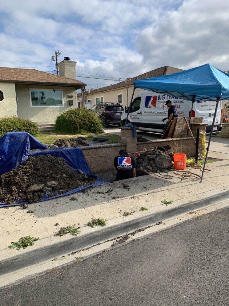 Construction work on a residential street with dirt piles, blue tarp, and a blue canopy over tools and equipment
