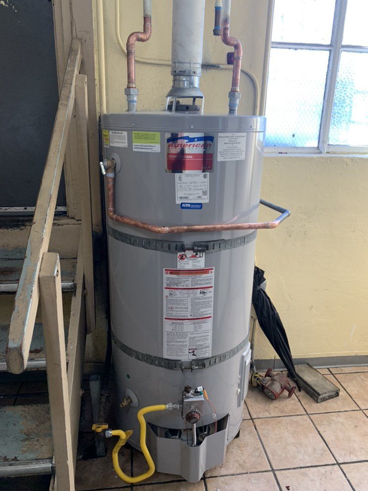 Water heater in a tiled utility area beside a window, with pipes and a yellow cord attached.