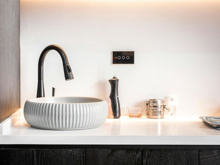 Modern bathroom sink with black faucet, white ribbed basin, and countertop accessories