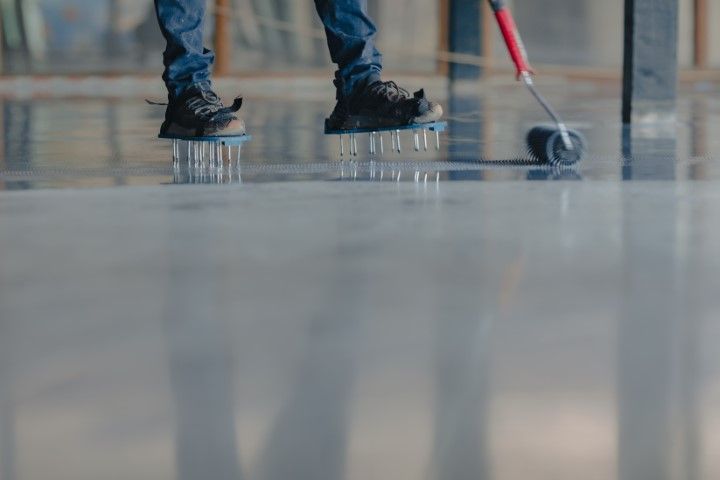 Person walking on a polished floor with a small wheeled cart reflected in the surface.
