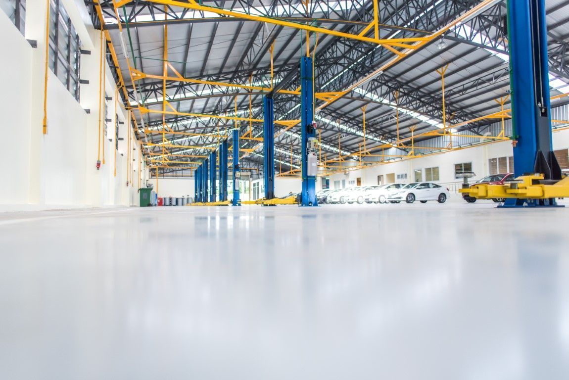 Bright industrial warehouse interior with blue steel columns and yellow overhead cranes