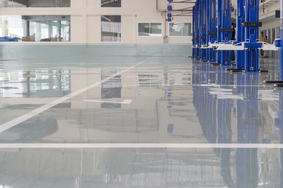 Glossy empty warehouse floor with blue industrial machinery along the right side
