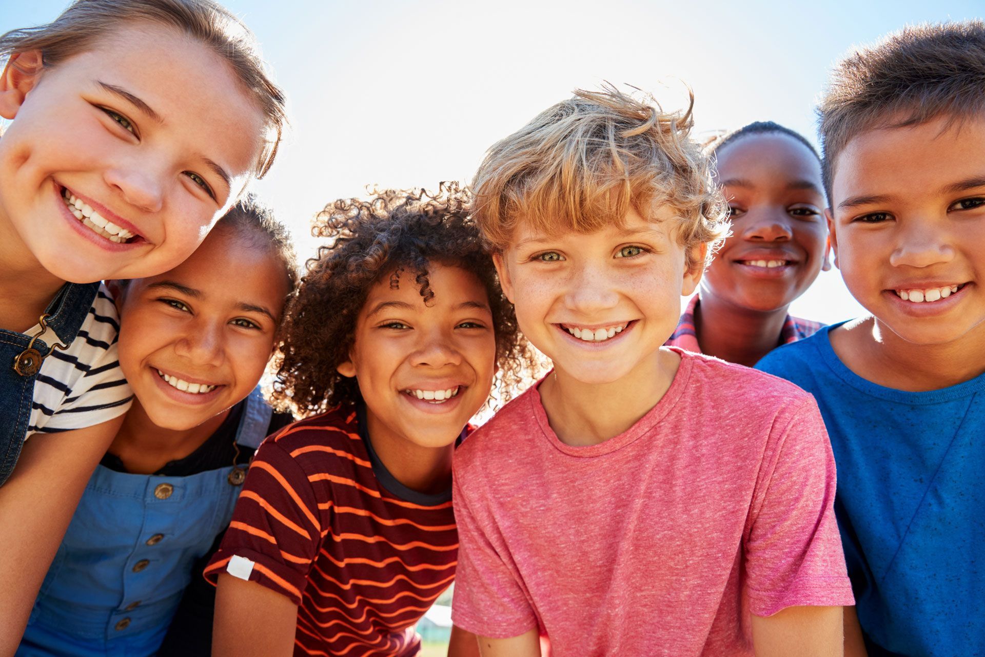 A group of children are posing for a picture together and smiling.