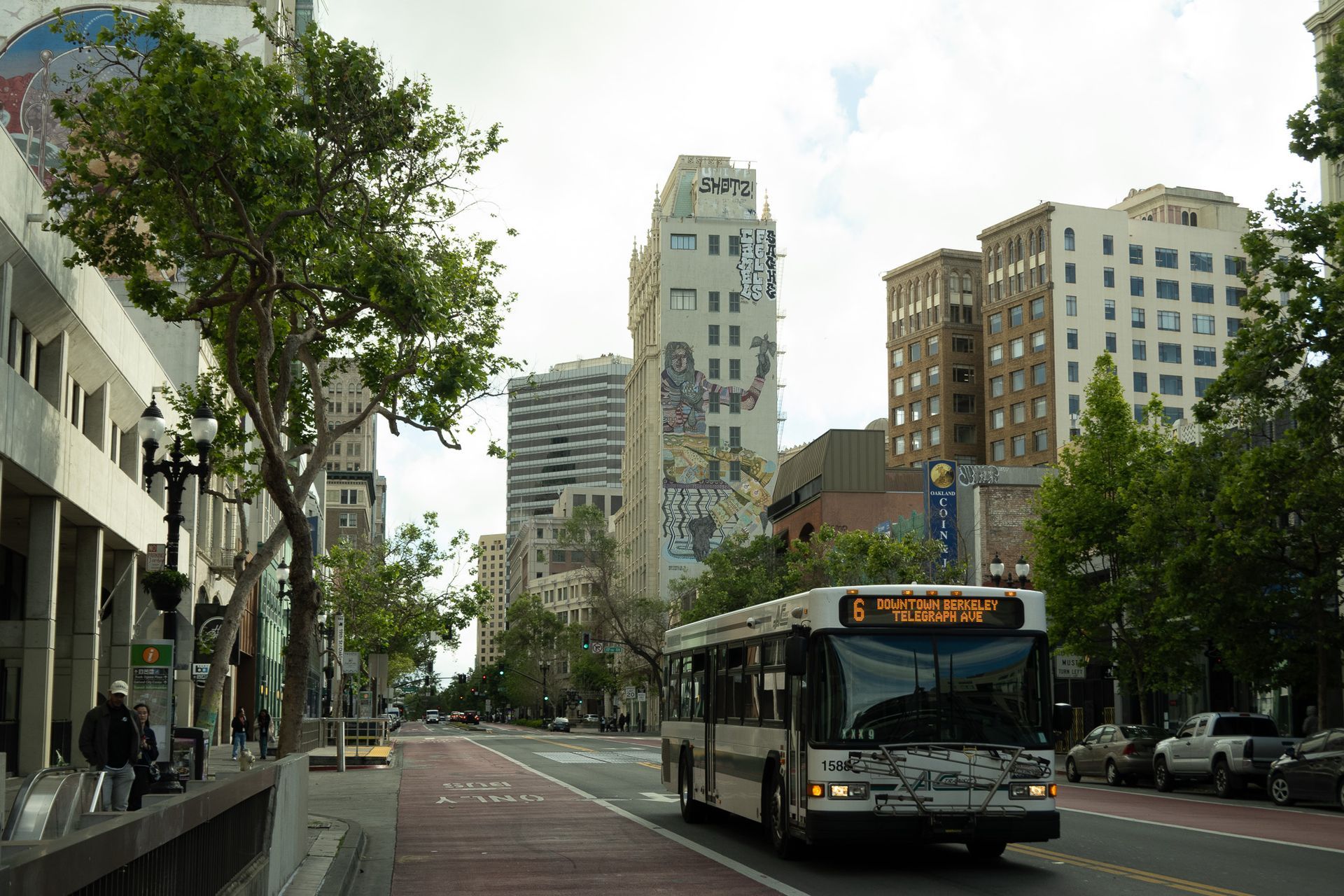 City street with a bus, tall buildings, and trees lining the road