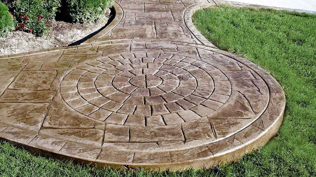 A concrete walkway with a circular design on it is surrounded by grass.