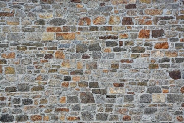 A close up of a stone wall with a lot of different types of bricks.