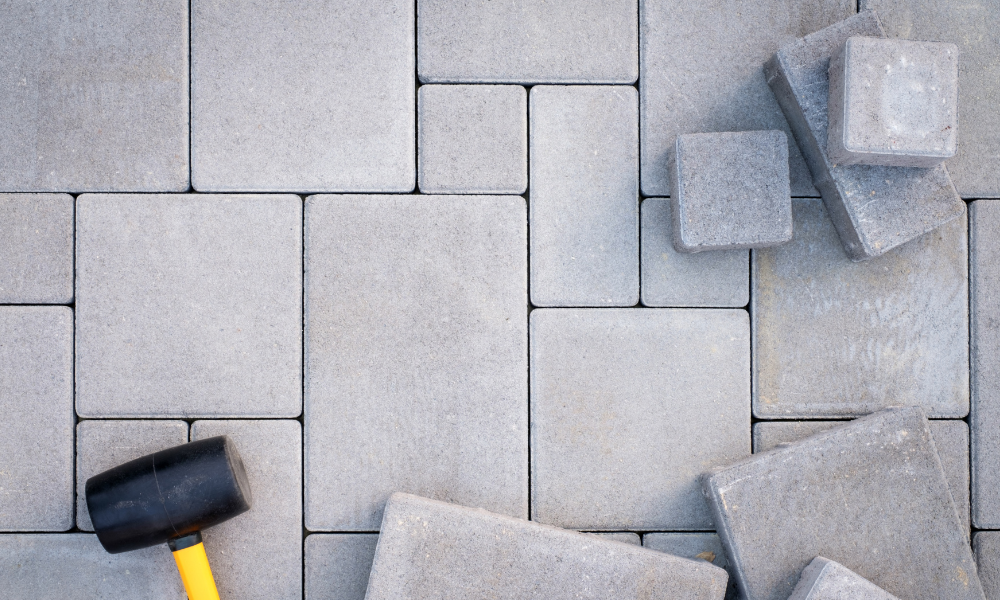 A hammer is laying on top of a pile of concrete tiles.