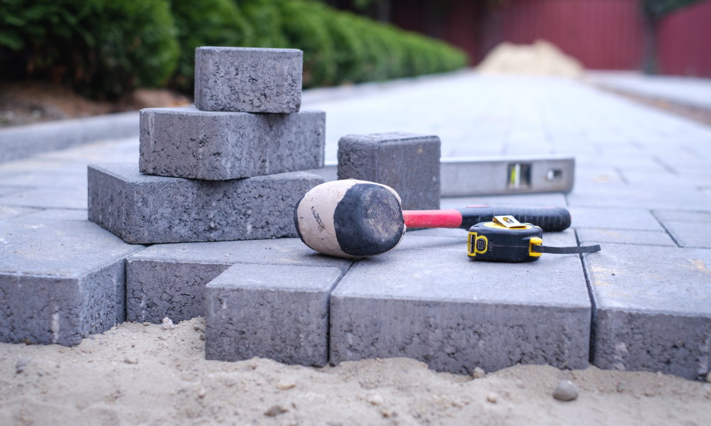 A hammer , level , tape measure and a rubber mallet are sitting on top of a pile of bricks.