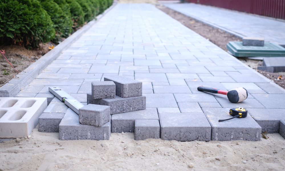 A sidewalk is being built with bricks and tools.