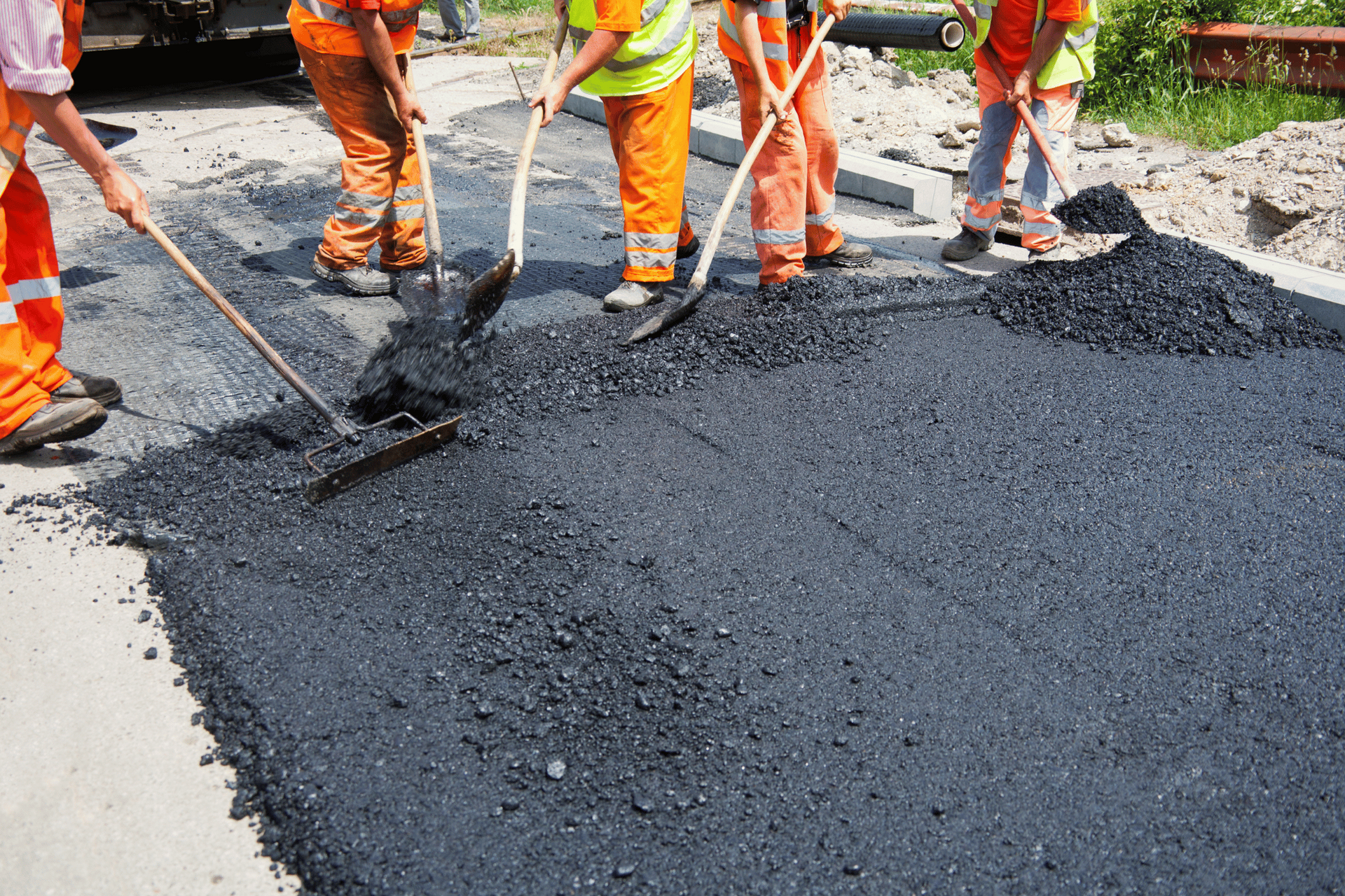 A group of construction workers are working on a road.