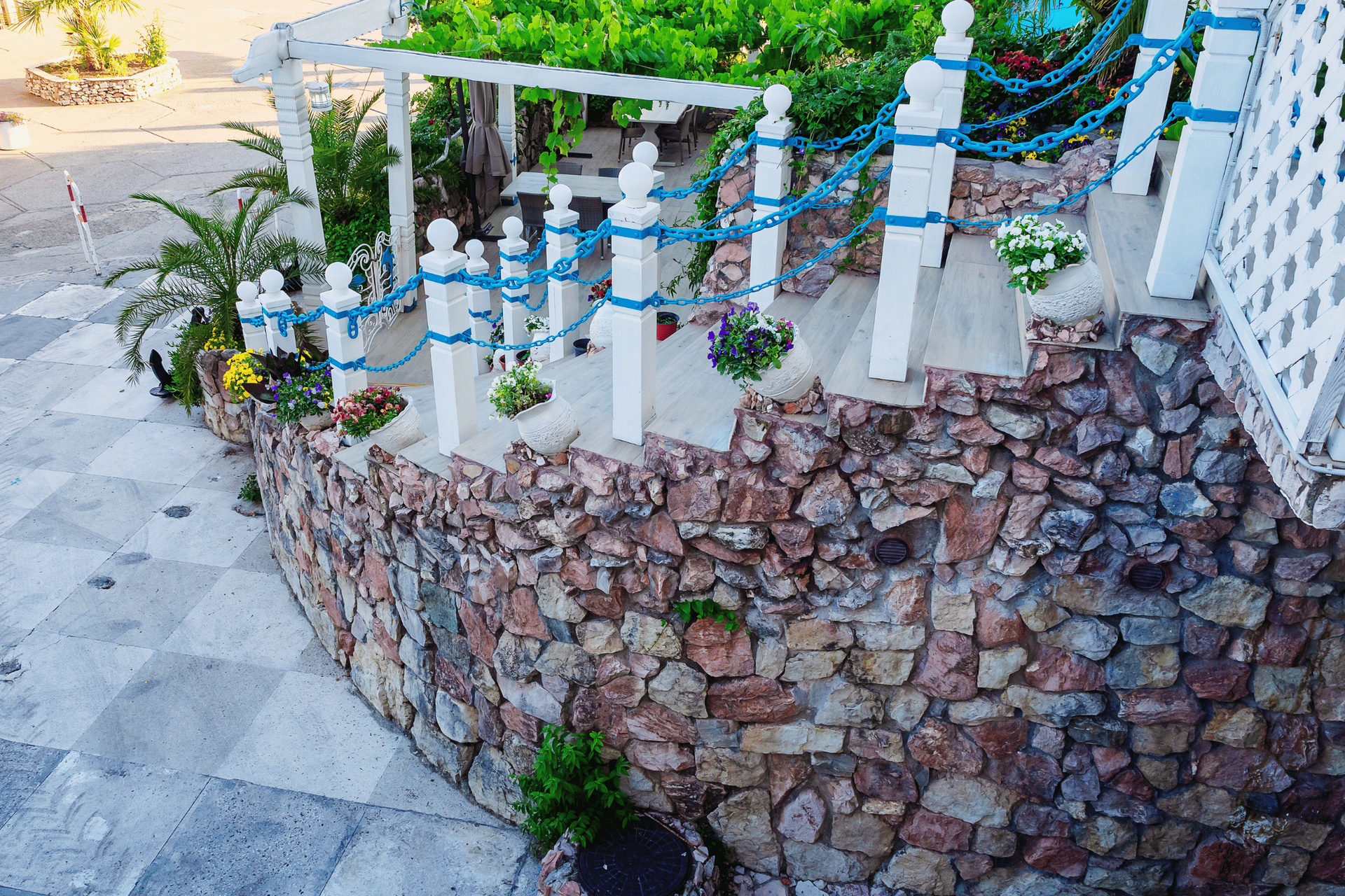 A stone wall with a white railing and blue ropes