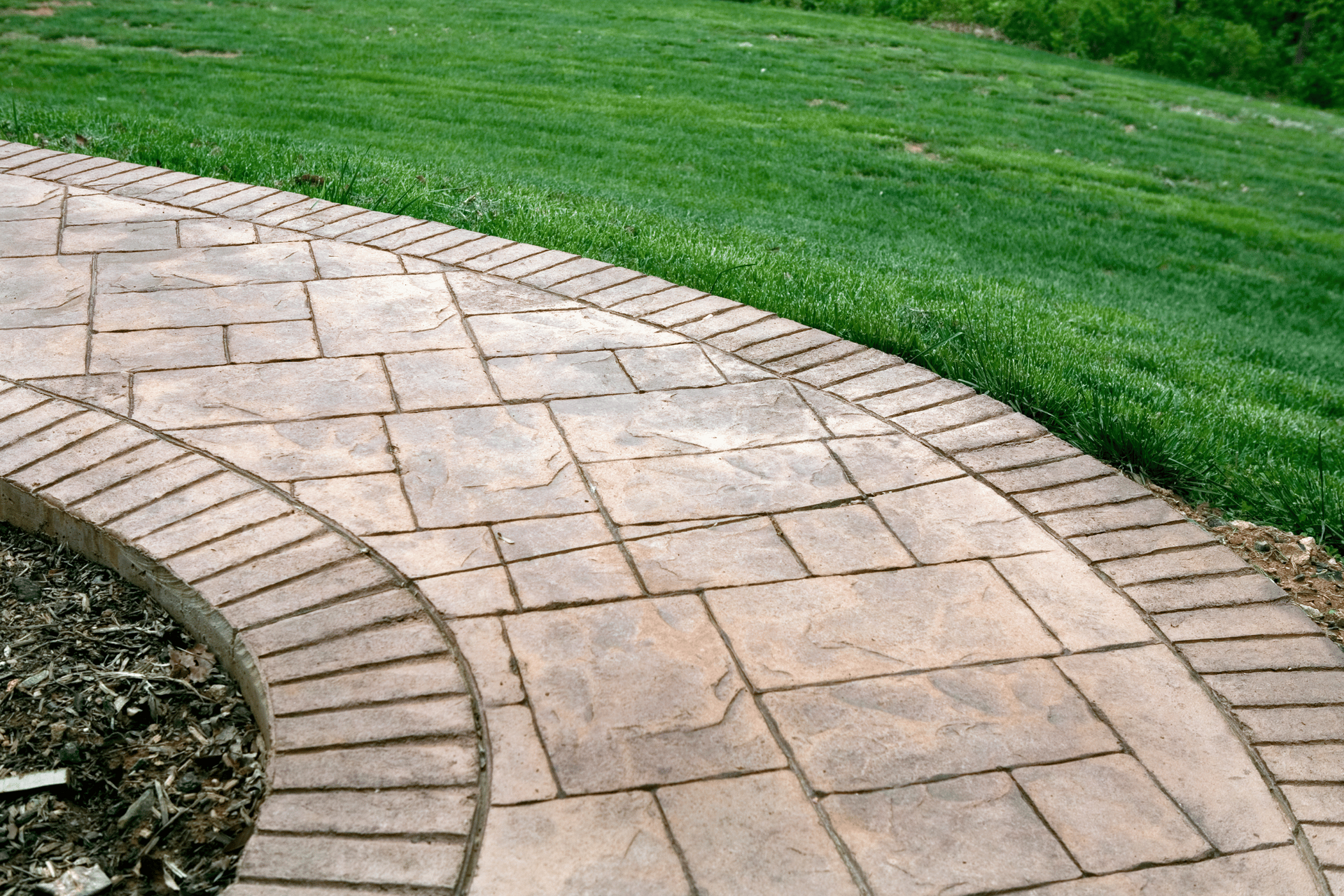 A brick walkway going through a lush green field