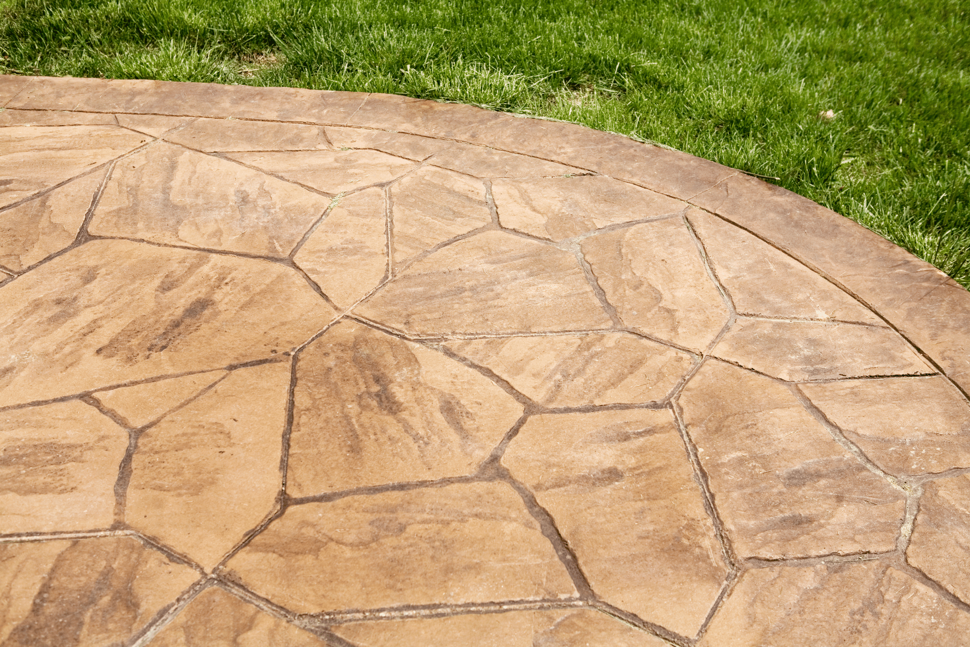 A concrete patio with a grassy lawn in the background